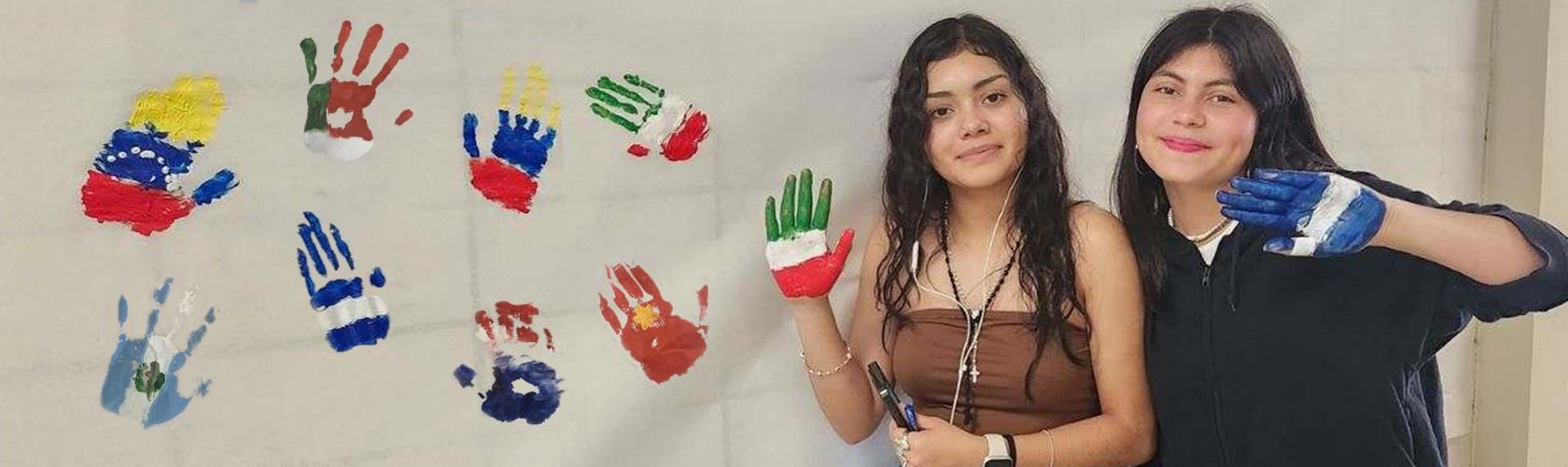 two latina students with flags painted on their hands to make a banner with flag handprints